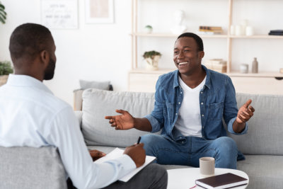 Cheerful man talking to psychologist on meeting at his office