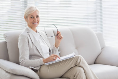 happy therapist with notes sitting on sofa in office