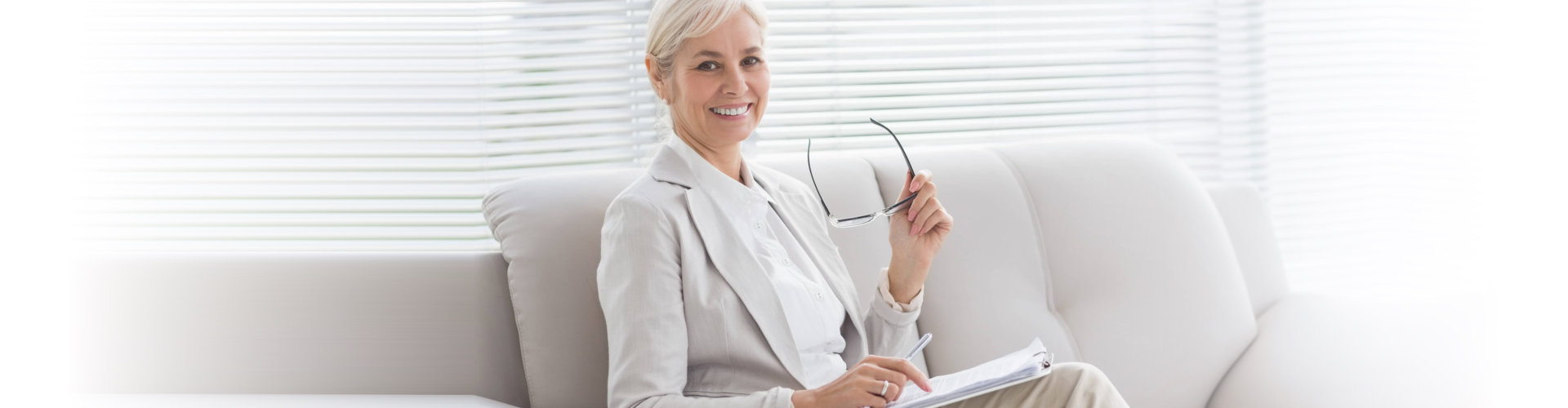 happy therapist with notes sitting on sofa in office